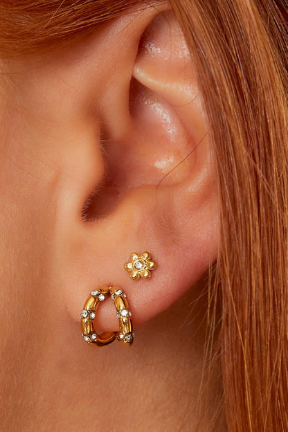Close-up of ear wearing gold floral mini stud earring paired with gold hoop earrings with rhinestones