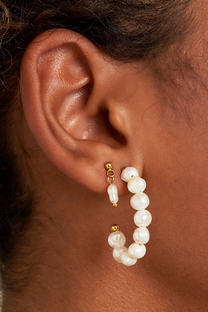 Close-up of ear wearing gold-tone short drop earrings with tiny freshwater pearls and larger pearl hoop earring