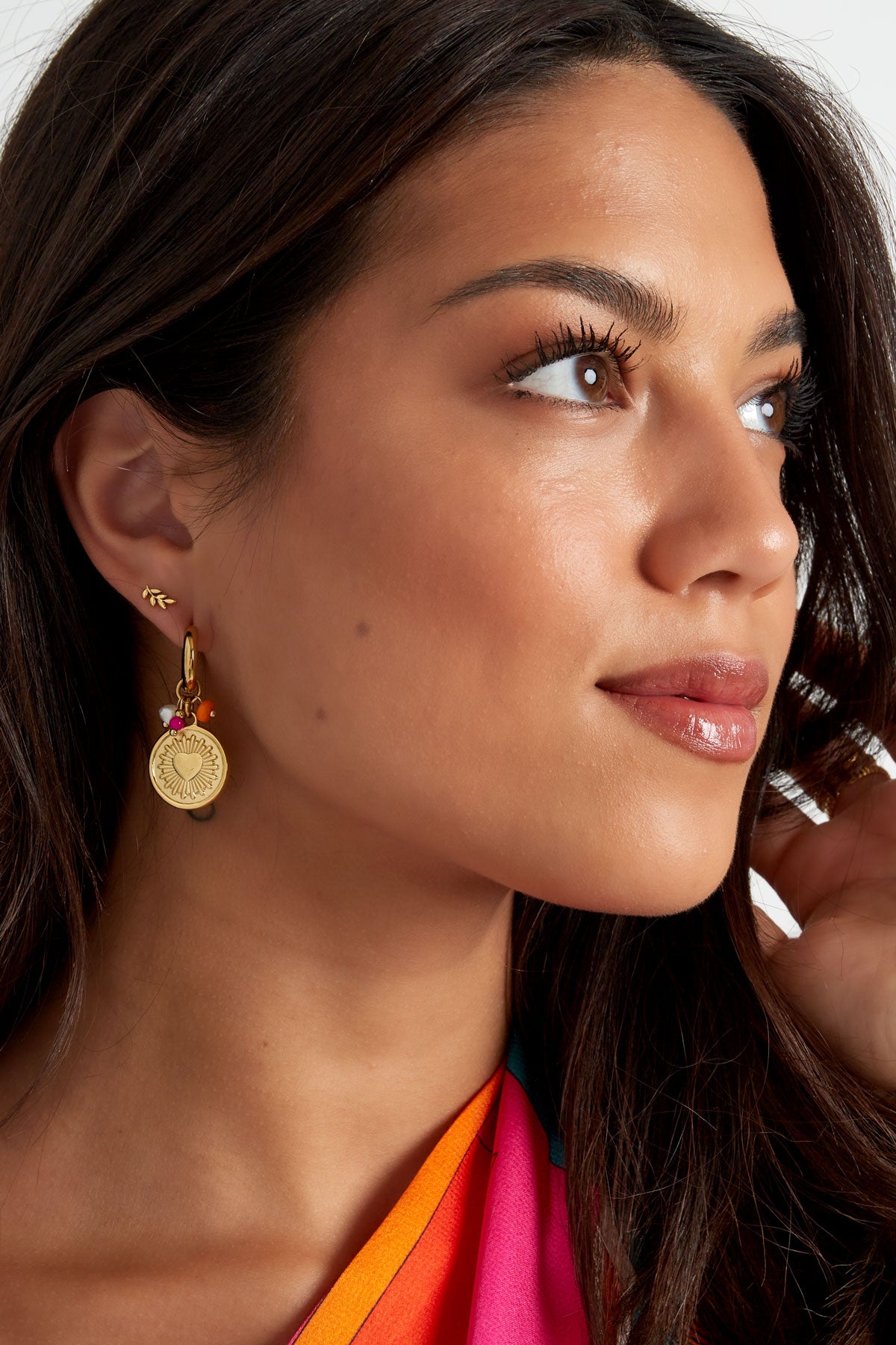 Model wearing gold leaf stud earrings paired with large gold charm hoop earrings, showcasing a youthful and aesthetic look