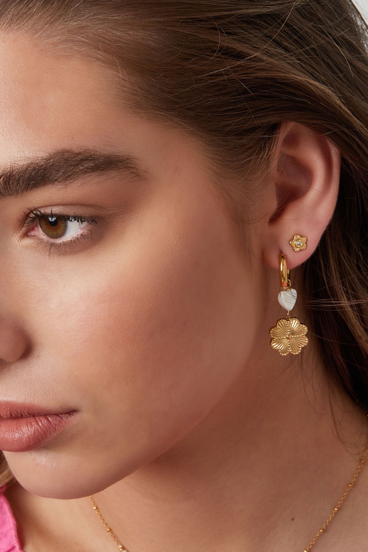 Model wearing small gold flower stud earrings paired with dangling gold flower and heart earrings