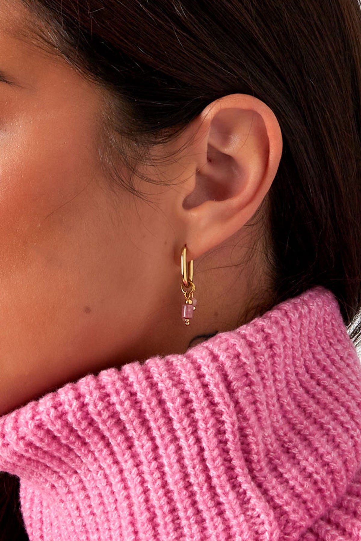 Close up profile of woman in pink sweater showing gold hoop earrings with small pink stone charms