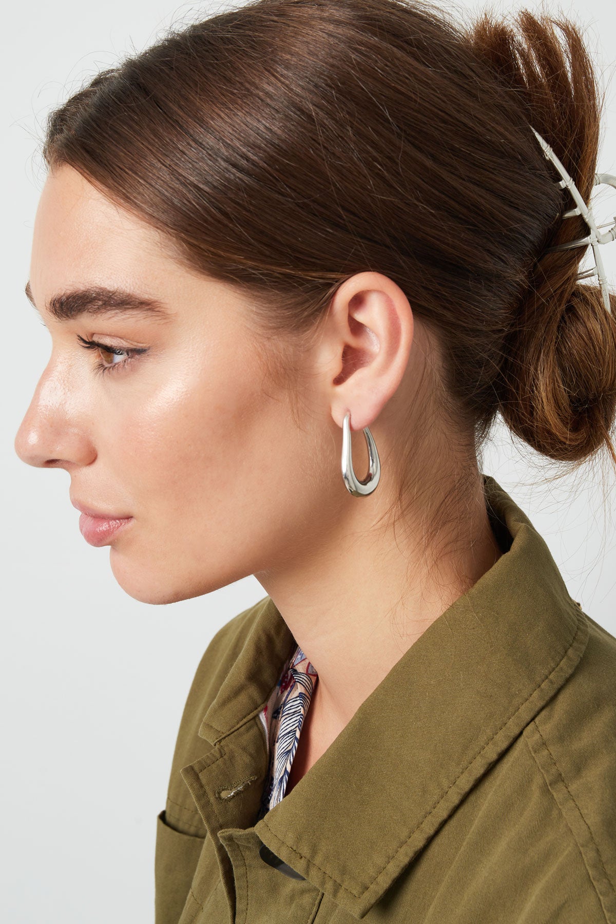 Model wearing silver teardrop hoop earrings, profile side view with hair pulled back
