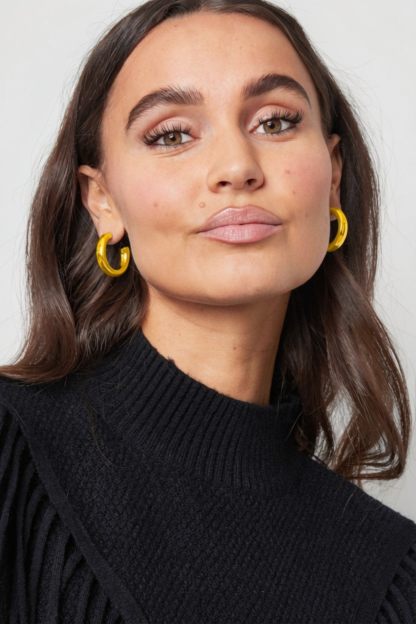Model wearing Big Mood Hoops: thick, polished gold-tone circular hoop earrings.