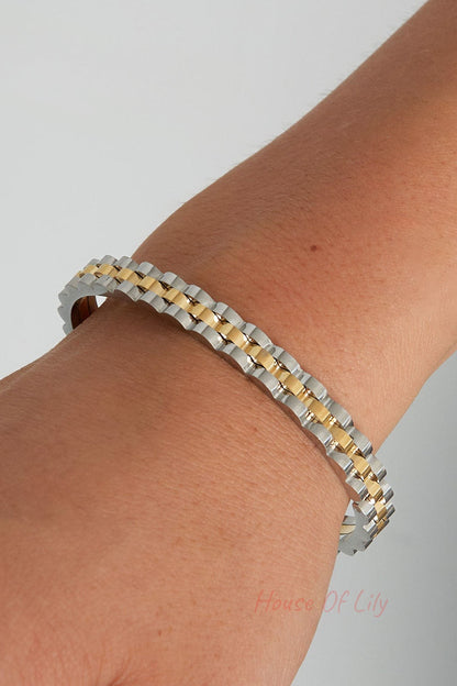Closeup of two-tone scalloped edge bangle bracelet on model wrist showing silver and gold details