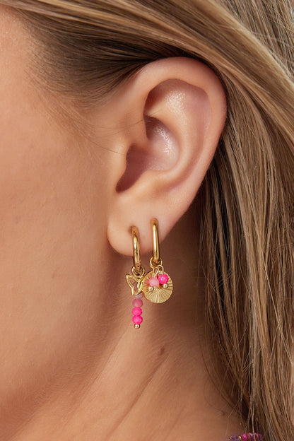 Close-up of gold hoop earrings with sunflower charm and pink beads worn on ear