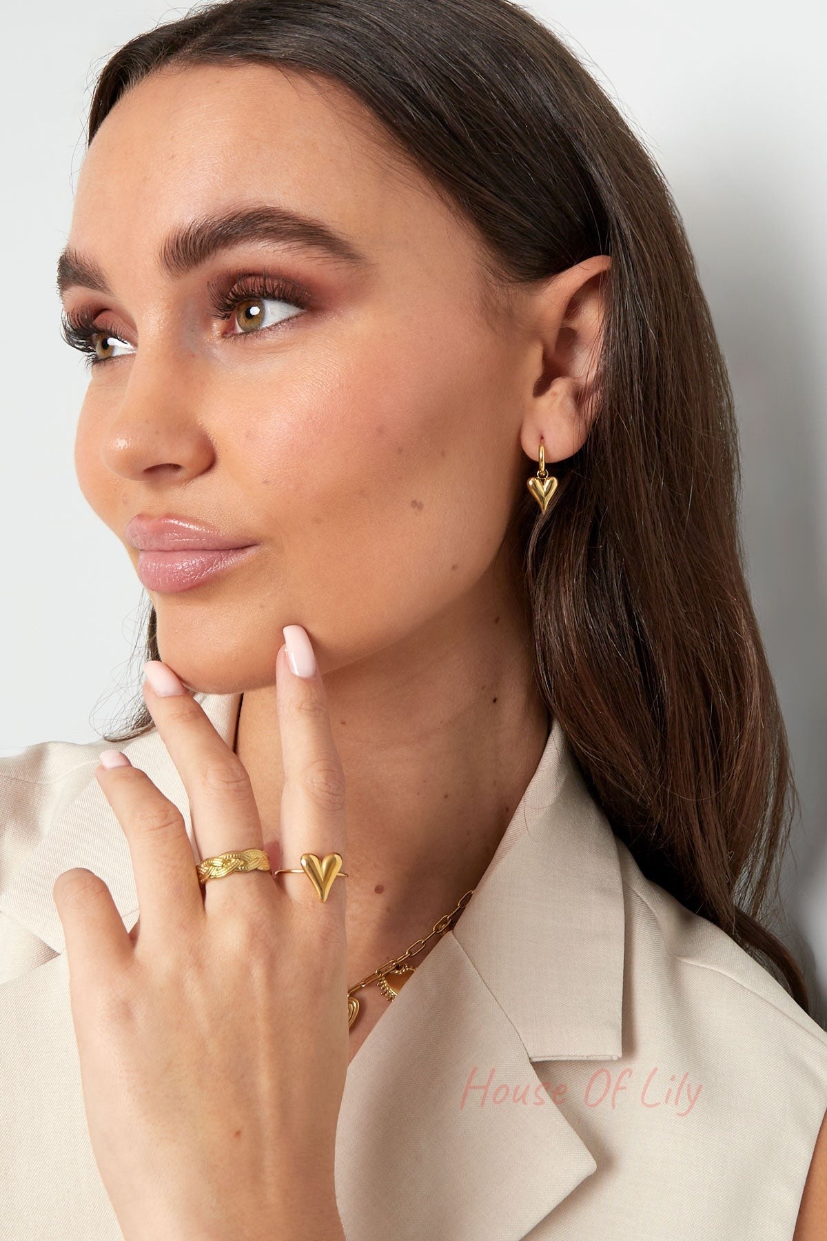 Woman wearing gold heart-shaped drop earrings, showcasing youthful and minimal style