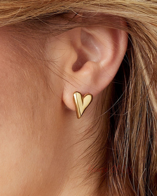 Close-up of ear adorned with gold heart stud earring showcasing smooth, polished minimal design
