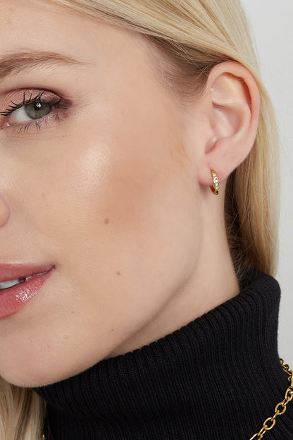 Pair of small gold hoop earrings with clear rhinestones shown on a white background