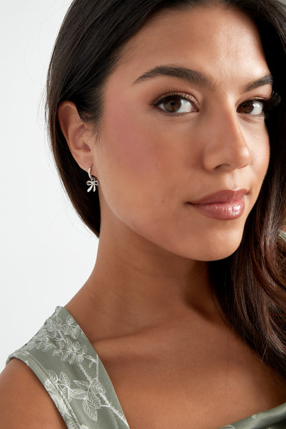 Silver bow charm hoop earrings on white background