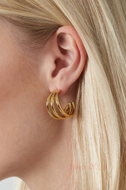 Side profile of model showing silver tone triple hoop earrings against blonde hair