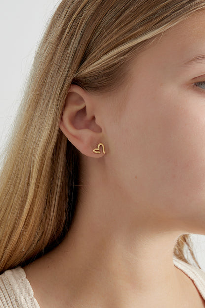 Close-up side view of gold-tone open heart stud earring worn on woman's ear with light skin and blonde hair