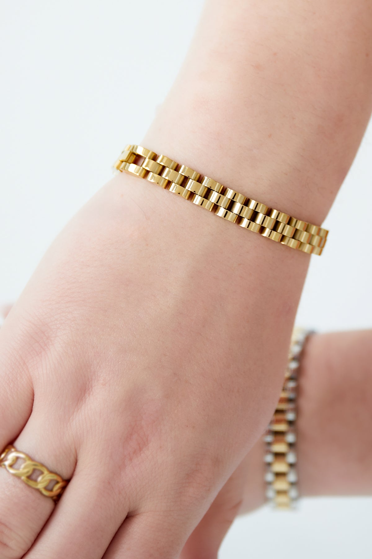 Gold-tone chain bracelet worn on wrist with matching rings, showing fit and shine