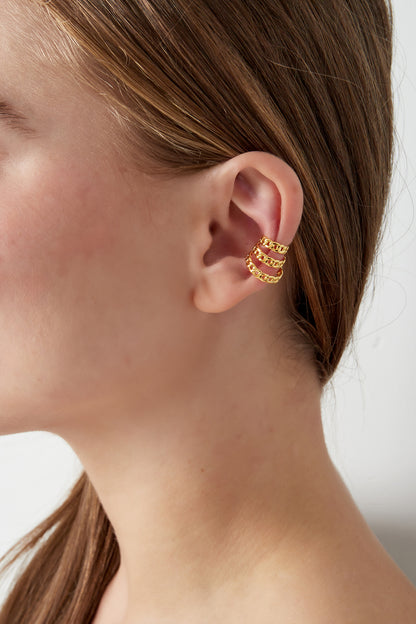 Side profile of woman wearing gold layered chain link ear cuff on upper ear