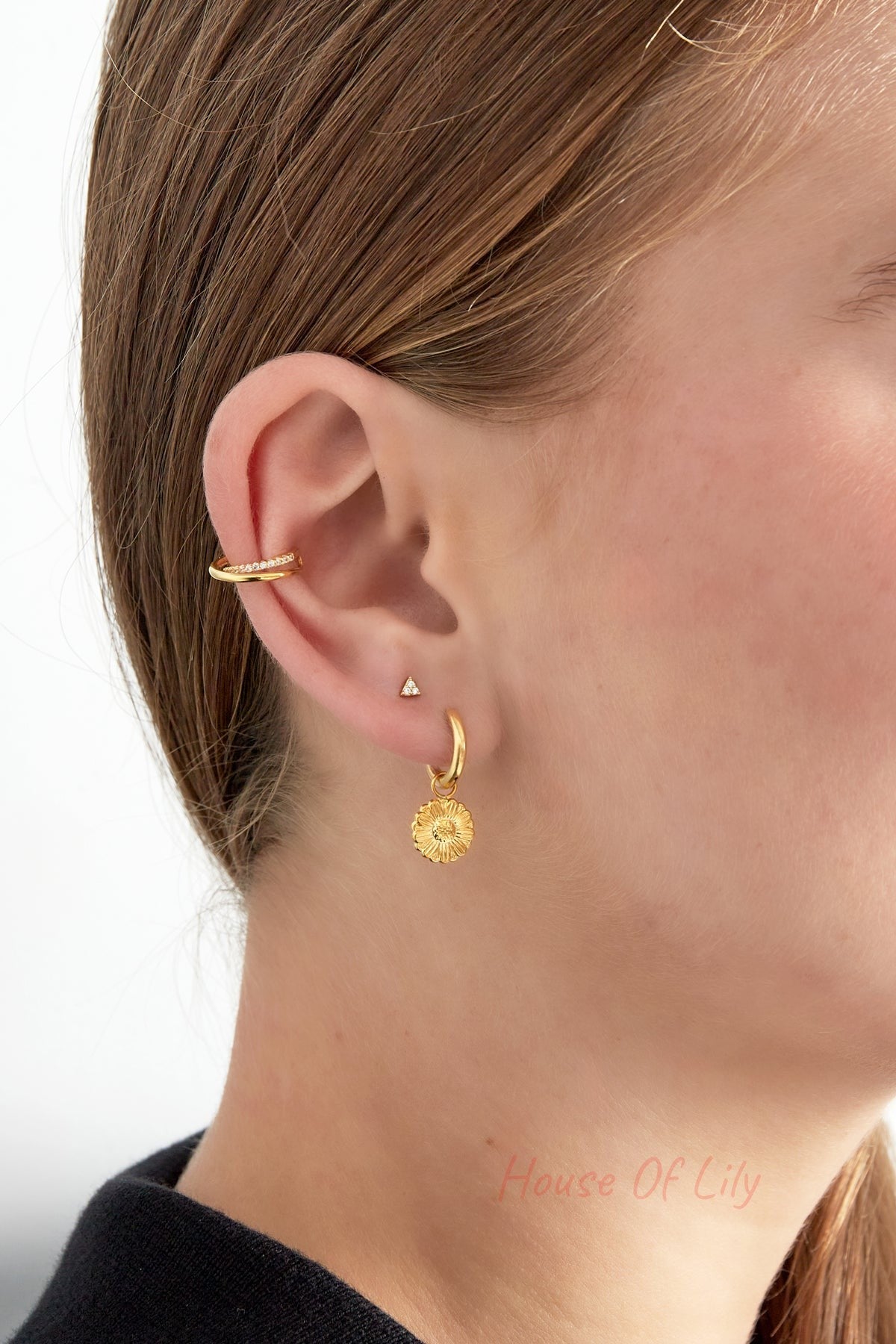 Close-up of woman’s ear with the spiral ear cuff on the upper ear and additional gold floral dangle earring on the lobe