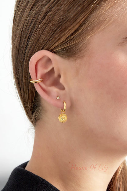 Close-up of woman’s ear with the spiral ear cuff on the upper ear and additional gold floral dangle earring on the lobe