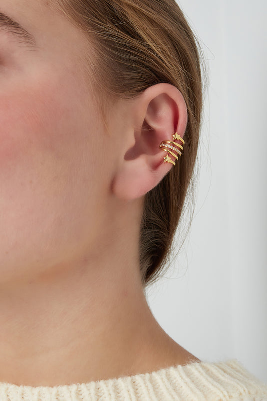 Close-up of gold-tone spiral star ear cuff worn on upper ear of a woman