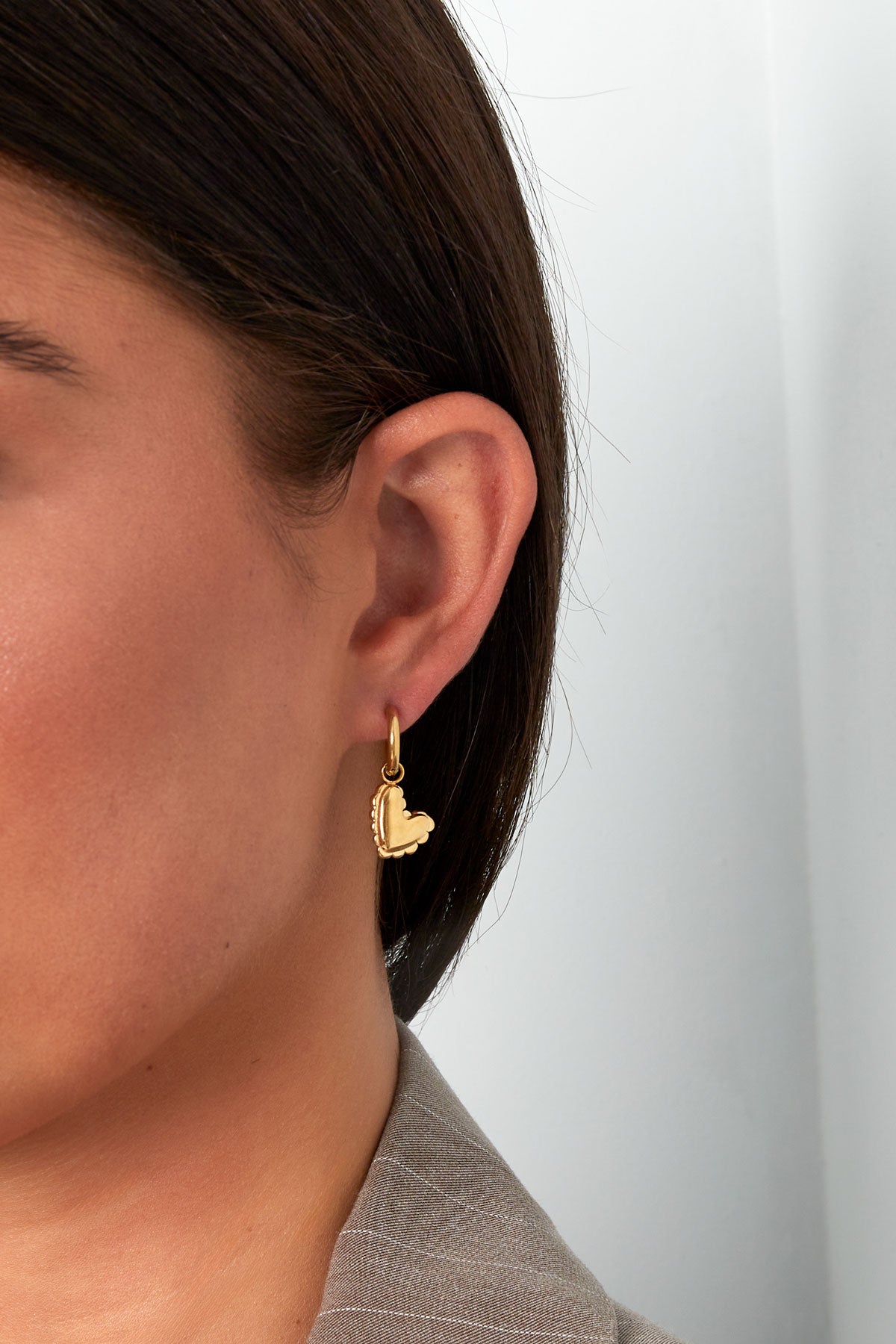 Gold heart charm drop earring worn on female ear showcasing size and minimal aesthetic