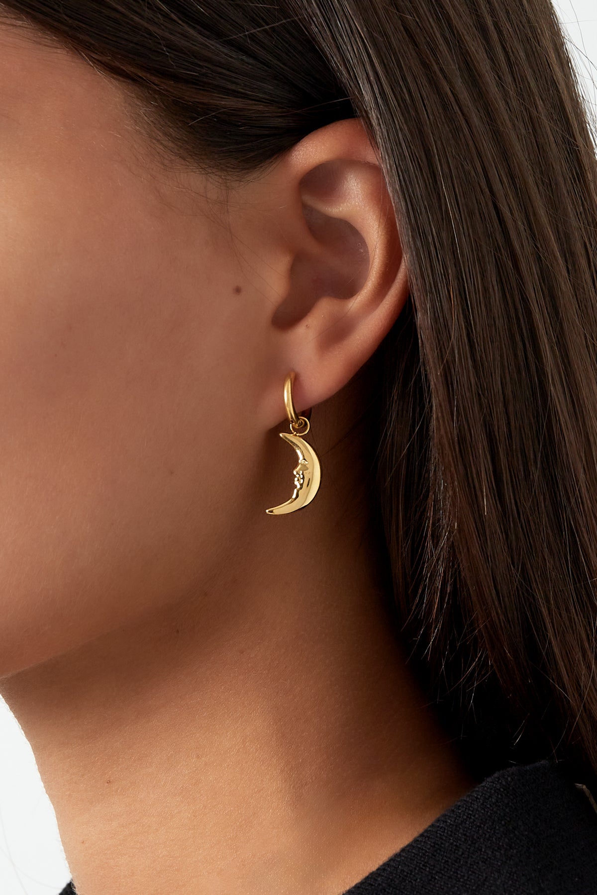 Close-up of a woman wearing gold moon face hoop earring with details visible