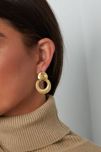 Model wearing gold textured hoop stud earrings paired with beige turtleneck sweater