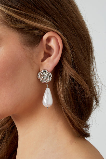 Silver rose and pearl drop earring worn on a woman's ear showcasing the size and style