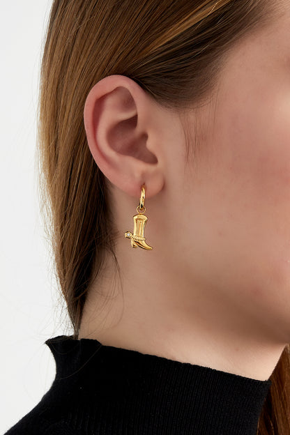 Close-up of a woman's ear wearing a gold cowboy boot charm drop earring with rhinestone accent