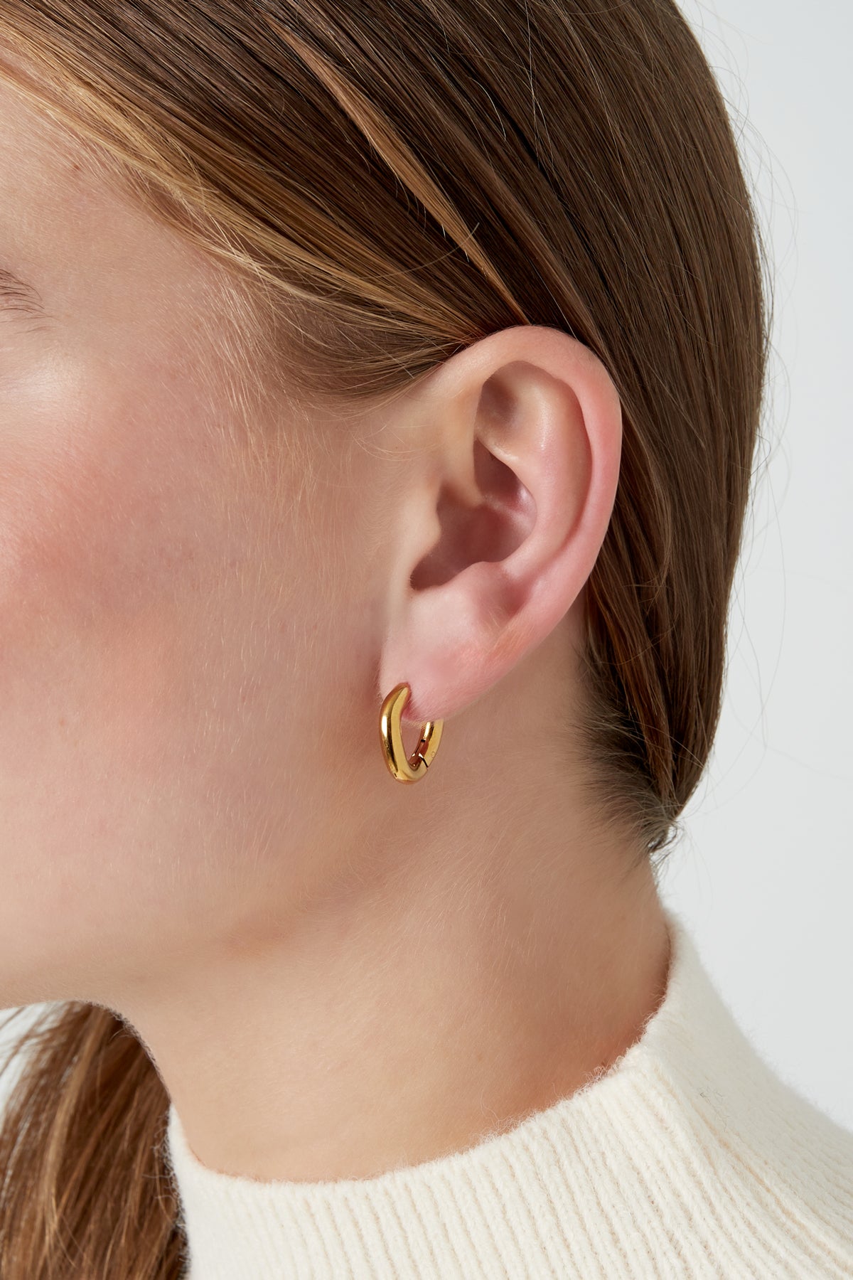 Close-up of model wearing smooth gold hoop earring showcasing minimalist style