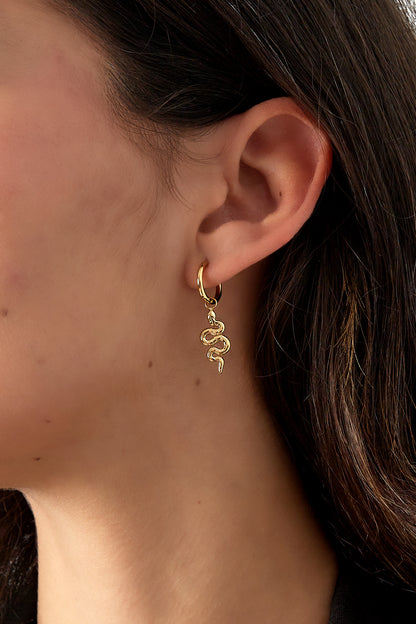 Close-up of gold snake charm hoop earring worn on a woman's ear with dark hair