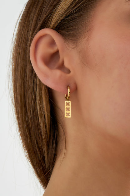 Close-up of a woman wearing one gold-toned triple cross bar drop earring