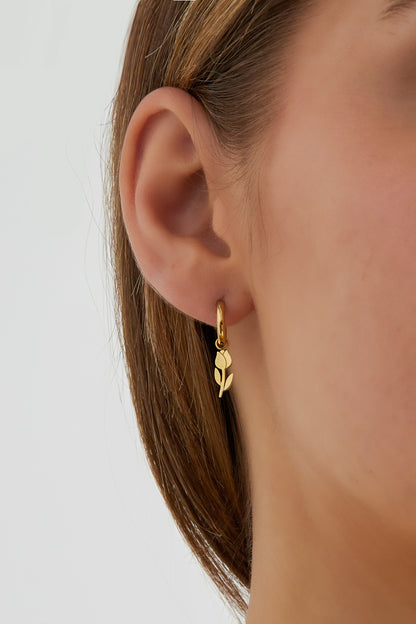 Model wearing one gold tulip drop hoop earring showing delicate youthful style