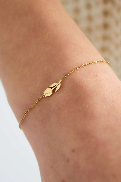 Gold tulip charm bracelet worn on a wrist, highlighting its fine chain and minimal floral design
