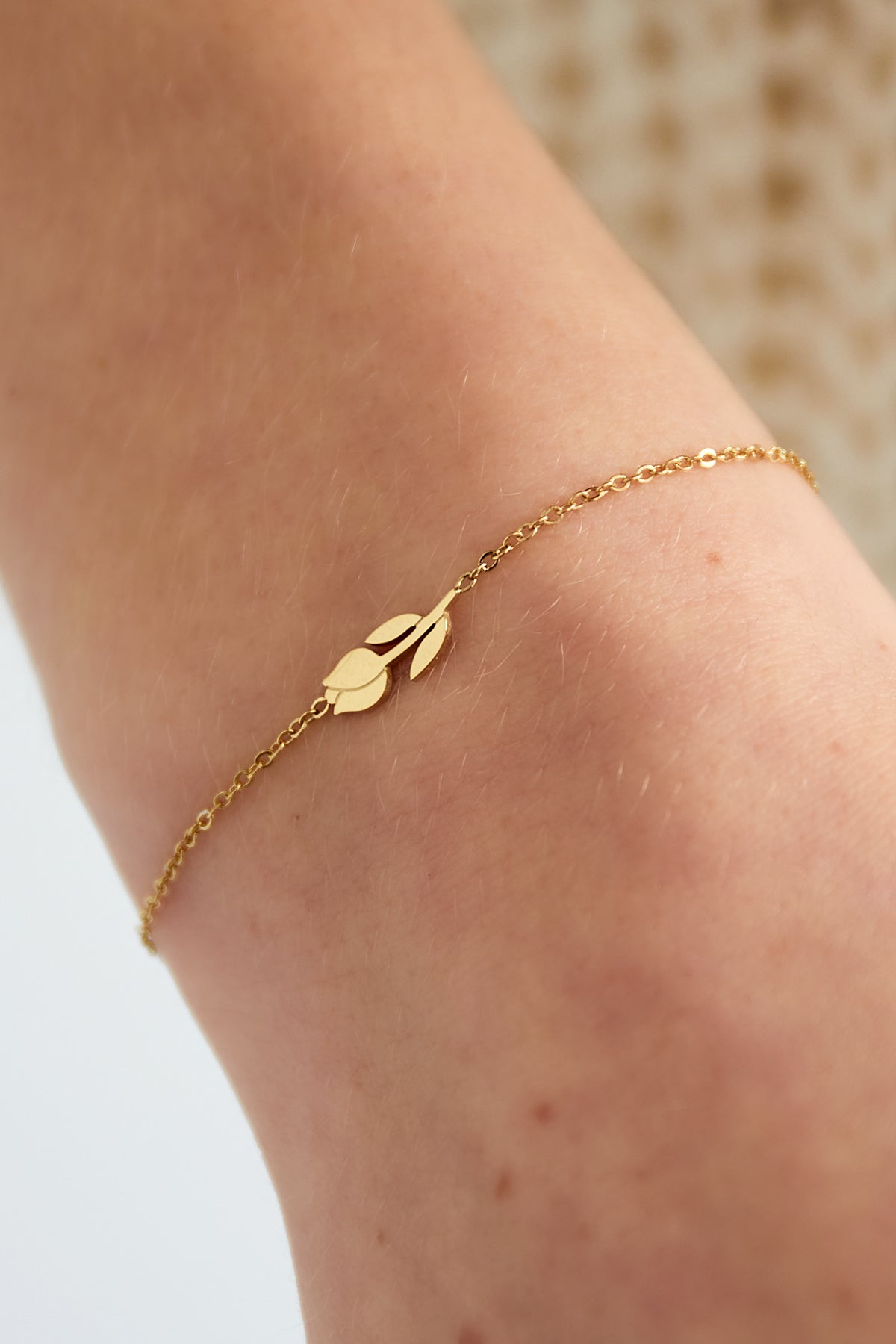 Gold tulip charm bracelet worn on a wrist, highlighting its fine chain and minimal floral design