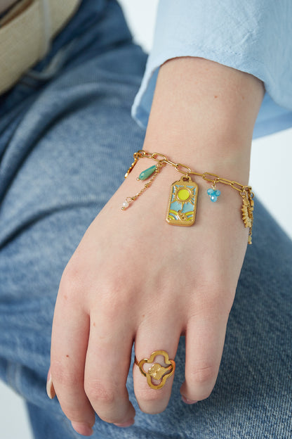 Woman wearing the gold-tone sunshine charm bracelet paired with a matching gold ring on her hand in casual outfit