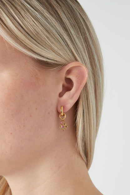 Close-up side view of gold-tone starlight charm hoop earring worn by blonde woman