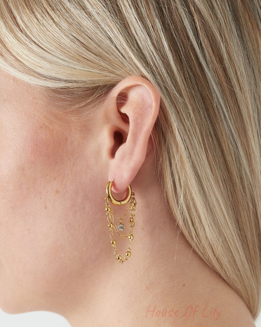 Close-up of a blonde woman wearing one gold chained hoop drop earring showing elegant layered chains