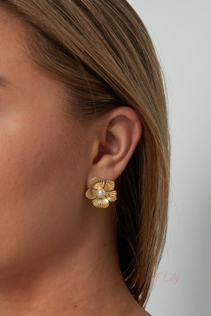 Model wearing gold floral pearl stud earrings showcasing the size and elegant fit
