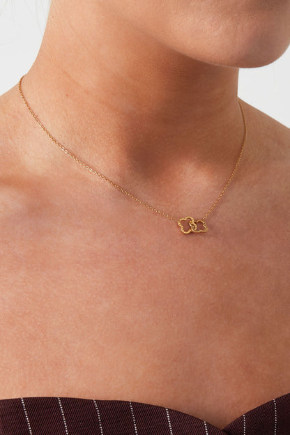 Close-up of woman wearing gold interlinked clover pendant necklace
