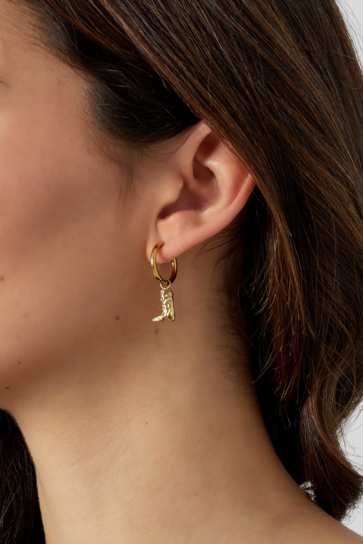 Model wearing gold cowgirl boot charm hoop earrings with close-up on ear