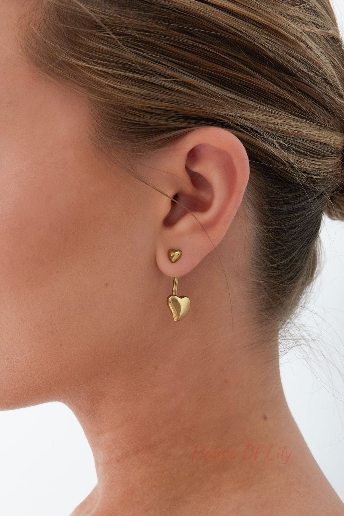 Model wearing gold double heart drop earrings showing small heart stud and larger heart drop