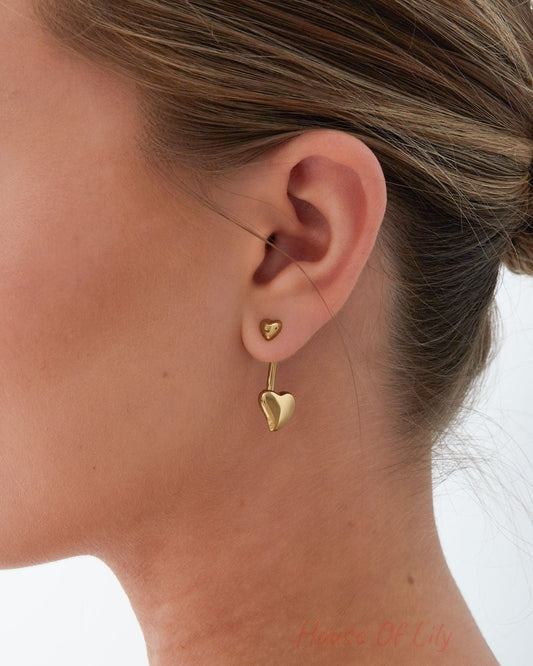 Model wearing gold double heart drop earrings showing small heart stud and larger heart drop