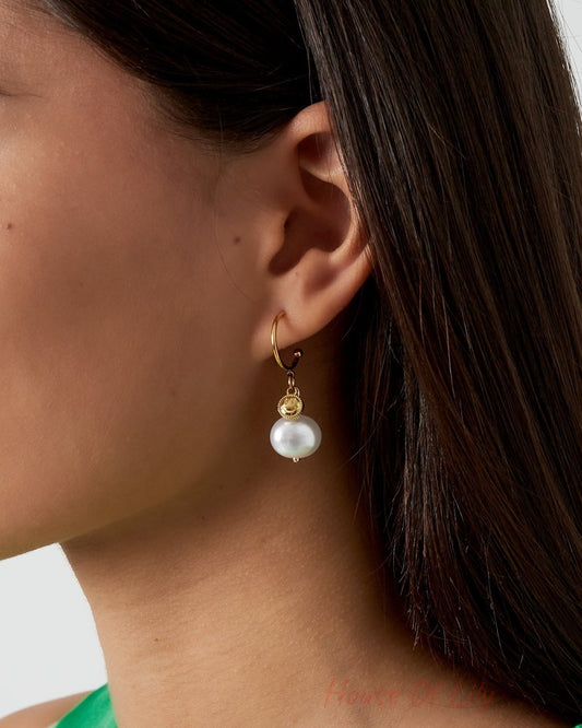 Close-up view of gold-tone Happy Glow drop earring worn by a model with dark hair and green top