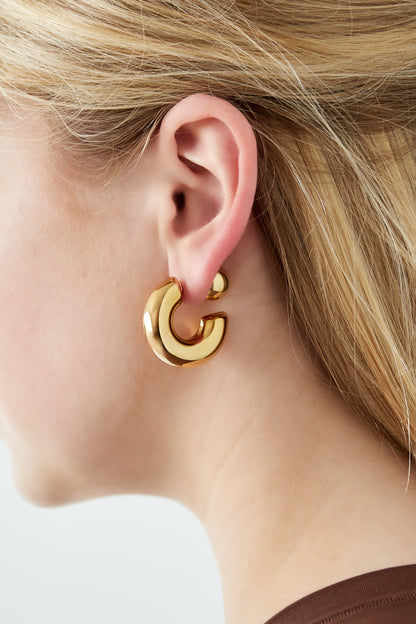 Close-up of woman wearing chunky gold hoop earring showing bold silhouette and polished finish