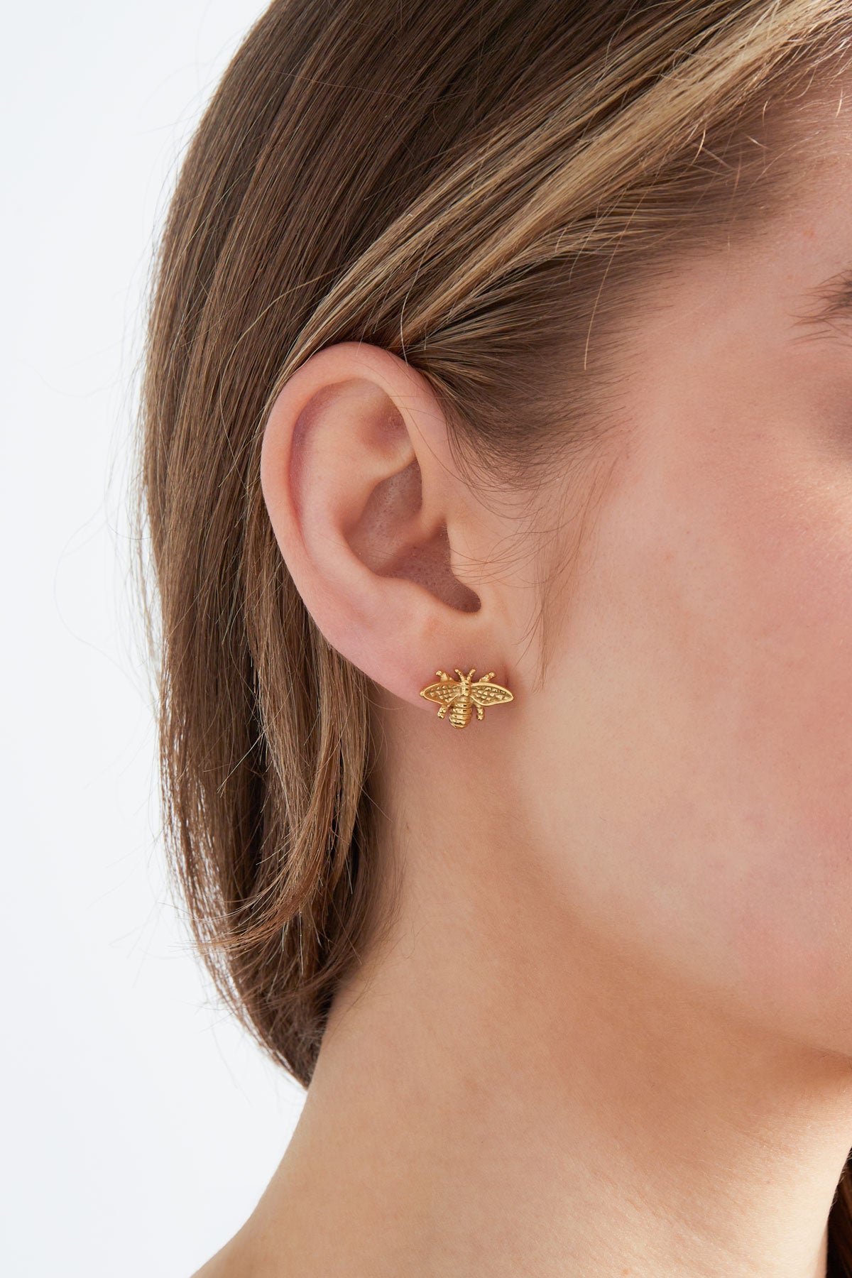 Model wearing gold bee stud earring, showcasing size and fit on ear