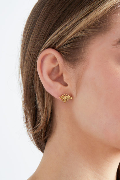 Model wearing gold bee stud earring, showcasing size and fit on ear