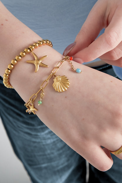 Bracelet worn on wrist alongside gold beaded bracelet, showing starfish and scallop shell charms