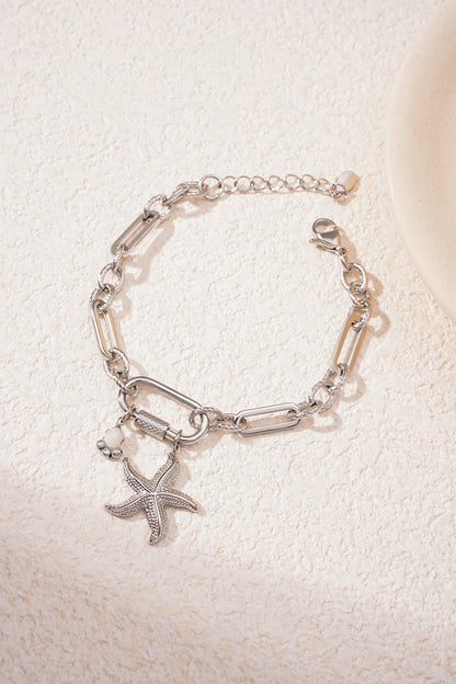 Silver starfish charm bracelet on textured light surface