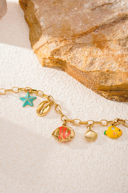 Sea charm bracelet displayed on textured surface with natural stone, highlighting each colourful charm