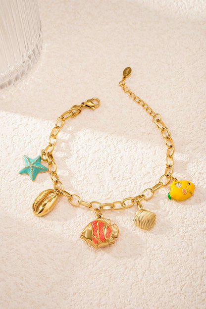 Playful ocean-themed charm bracelet lying flat on sandy textured surface with vibrant turquoise starfish charm