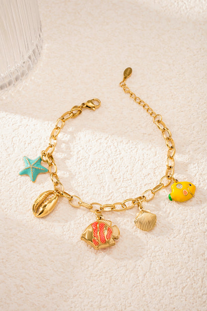 Playful ocean-themed charm bracelet lying flat on sandy textured surface with vibrant turquoise starfish charm