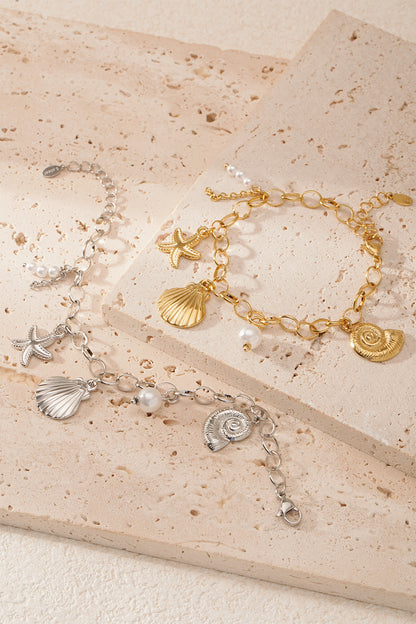Gold and silver seaside charm bracelets laid on textured beige tiles highlighting the design and materials