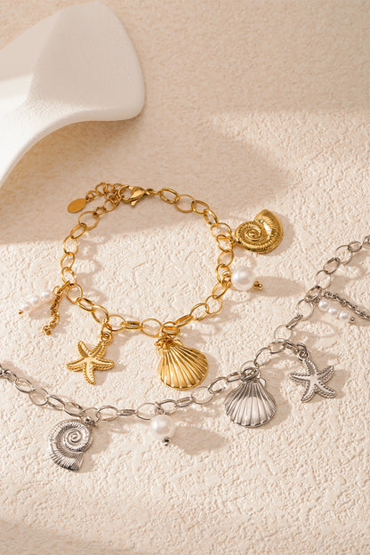 Detailed view of silver seaside charm bracelet with starfish, scallop shell, nautilus shell and pearl charms on white background